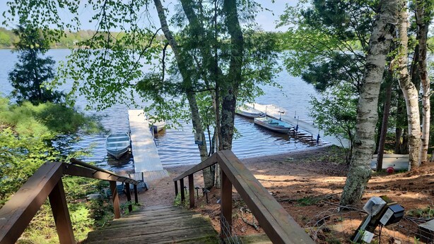 A wooden staircase leading to a dock with boats, surrounded by trees and a calm lake.
