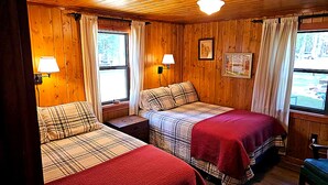 Een kamer in chaletstijl met twee bedden, houten wanden en een groot raam.