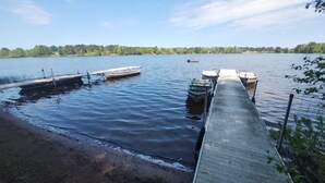 A calm lake with a wooden dock extending into the water, surrounded by trees.