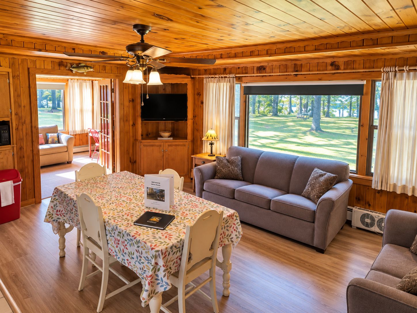 A cozy cabin interior with a dining area, sofa, and a television.