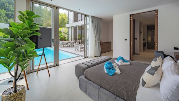 A modern hotel room with a large bed, a balcony with a pool view, and a dining area. - GRAND VIEW Residences Villa with Pool (Choeng Thale)
