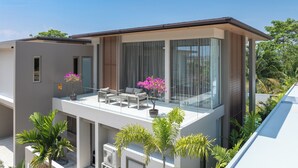 A modern two-story building with a balcony, large windows, and potted plants. - GRAND VIEW Residences Villa with Pool (Choeng Thale)
