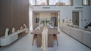 A modern dining area with a long table, chairs, and a decorative centerpiece. - GRAND VIEW Residences Villa with Pool (Choeng Thale)