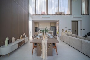 A modern dining area with a long table, chairs, and a decorative centerpiece. - GRAND VIEW Residences Villa with Pool (Choeng Thale)