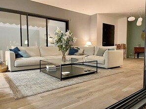 A modern living room with a sofa set, a glass coffee table, and a large window. - Contemporary villa with pool near Aix-en-Provence (Éguilles)