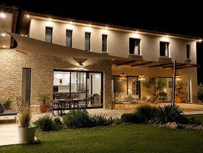 A modern house with a stone facade, large windows, and a patio area with outdoor furniture. - Contemporary villa with pool near Aix-en-Provence (Éguilles)