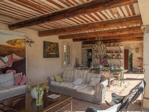 Un salon meublé comprenant un canapé, des fauteuils, une table basse et un coin repas avec une table et des chaises.