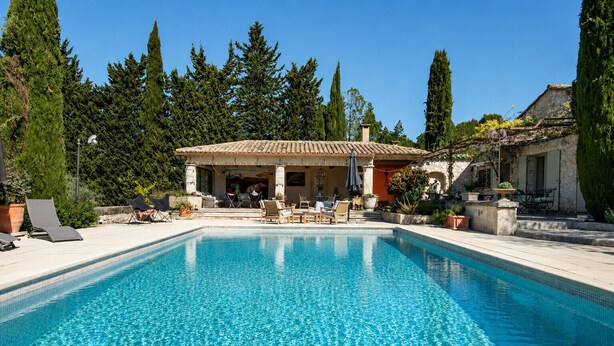 Una piscina amb gandules i una zona de pati coberta.