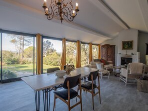 A spacious room with a large dining table, chairs, a fireplace, and a view of the outdoors. - Villa Toscane – Countryside Estate with Pool (Pernes-les-Fontaines)