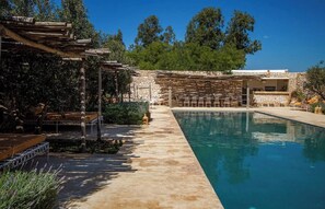 Ein Pool mit Steinmauer und Sitzgelegenheiten im Freien.
