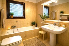 A bathroom with a bathtub, toilet, sink, and window with blinds. - Spacious Apartment in Luino for 5 (Luino)