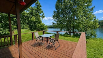 Un terrazzo in legno con tavolo e sedie che si affaccia su un lago.