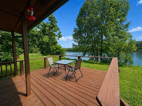 Eine Holzterrasse mit Tisch und Stühlen mit Blick auf einen See.