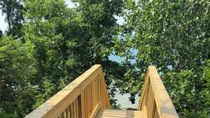 A wooden deck with a gate, surrounded by greenery.