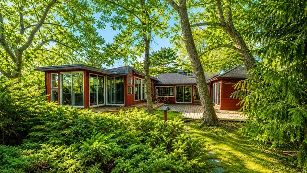 Une maison moderne dotée de grandes fenêtres en verre, entourée d’un luxuriant feuillage verdoyant.