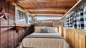 Une chambre à coucher de style cabane en bois, avec un lit, des oreillers, un rideau à carreaux et une décoration en forme d’étoile.