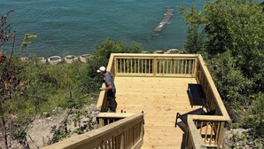A wooden deck leading to a beach with a person standing on it.