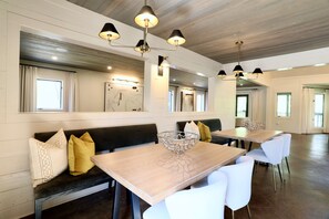Un comedor amplio con techos altos, vigas de madera e iluminación colgante moderna.