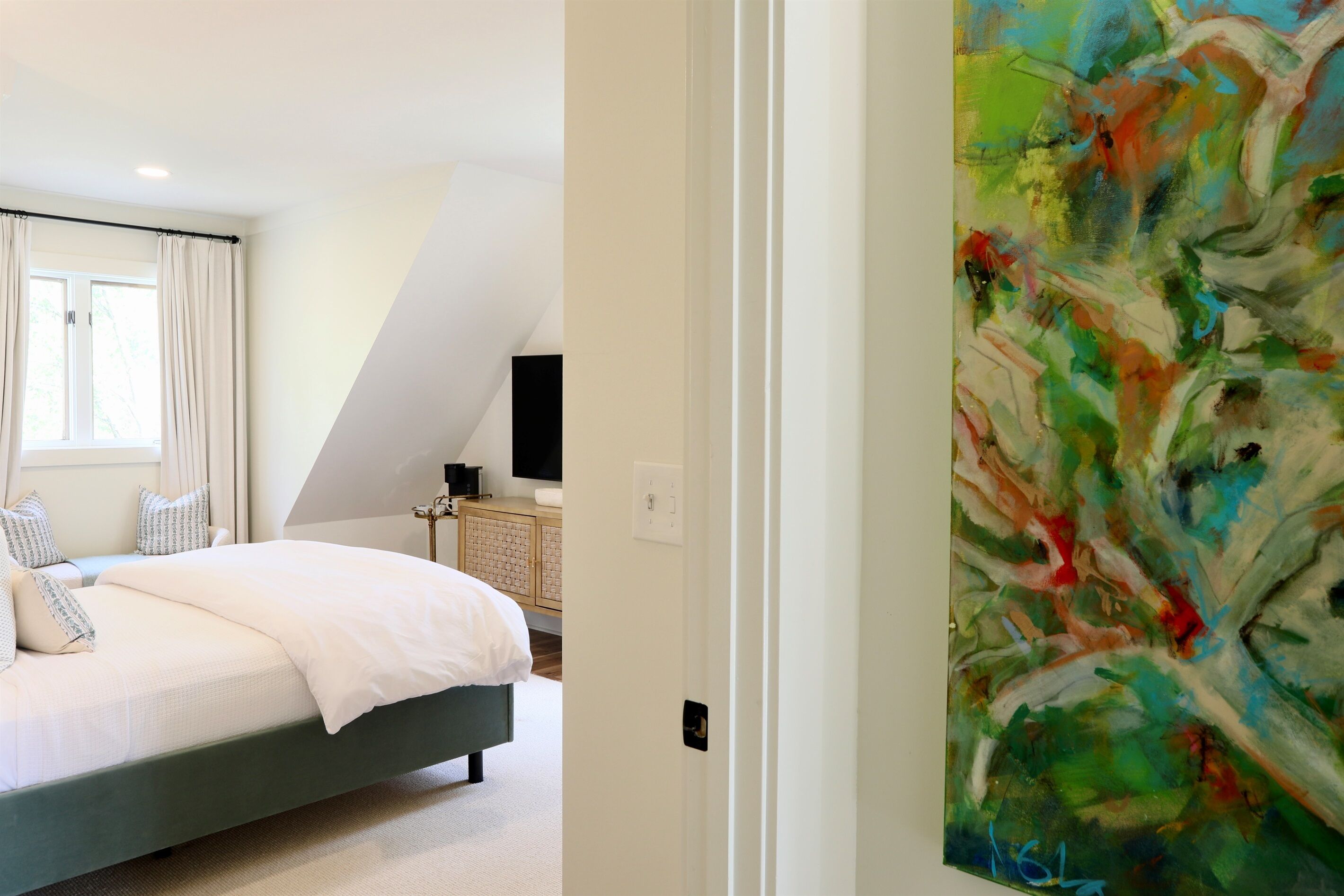 Une chambre à coucher avec un lit, des rideaux, une télévision et une armoire.