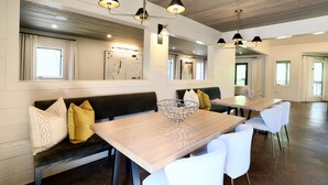 A spacious dining area with high ceilings, wooden beams, and modern pendant lighting. - "The Ravine Cabin" by OVR (Oxford)
