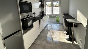 Una cuina moderna amb armaris blancs, forn integrat i nevera.