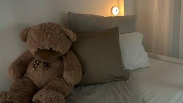 Ein Stockbett mit einem Teddybären auf der Unterliege, einem Kissen und einer Nachttischlampe.