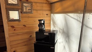 Eine kompakte Küche mit Kaffeemaschine, Mikrowelle und Kühlschrank.