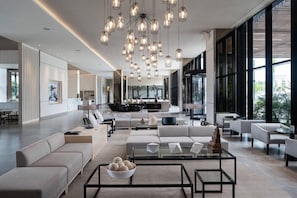 A modern living room with a sofa, coffee table, and hanging lights. - AC Hotel Kingston Jamaica (Kingston)