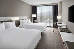 A hotel room with two beds, a desk, a chair, and a TV. - AC Hotel Kingston Jamaica (Kingston)