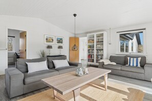 A spacious living room with two grey sofas, a wooden coffee table, and a bookshelf. - Spacious holiday home 150 m from the beach (Ålbæk)