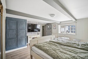 A bedroom with a bed, a dresser, a television, a window with a view, and a door. - Spacious holiday home near Ribe for 11 (Ribe)