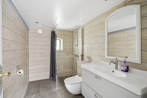 Une salle de bain comprenant des toilettes, un lavabo, un miroir, une douche et un porte-serviettes.