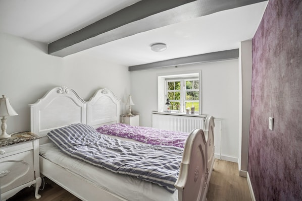A bedroom with a bed, nightstands, a window with a view, and a door.