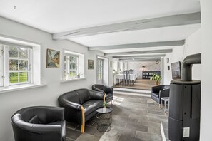 A modern living room with leather sofas, a round coffee table, a fireplace, and a dining area in the background. - Spacious holiday home near Ribe for 11 (Ribe)