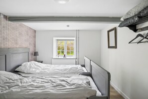 A bedroom with two beds, a window with a view, a radiator, and a coat rack. - Spacious holiday home near Ribe for 11 (Ribe)