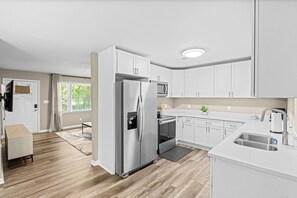 A modern kitchen with white cabinets, stainless steel appliances, and a large island with a sink. - Large Home/ Fully Appointed /Game Room! (Mableton)