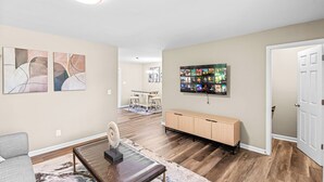 Ein Wohnzimmer mit Sofa, Couchtisch, Kunstwerken, einer TV-Wandhalterung und einem Holzschrank.