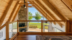 A high-ceilinged room with a stone fireplace, wooden beams, and a view of a lake. - Sleeps 6 | Lake Access | Near Wineries | Pet Friendly |Pool (Bradford)