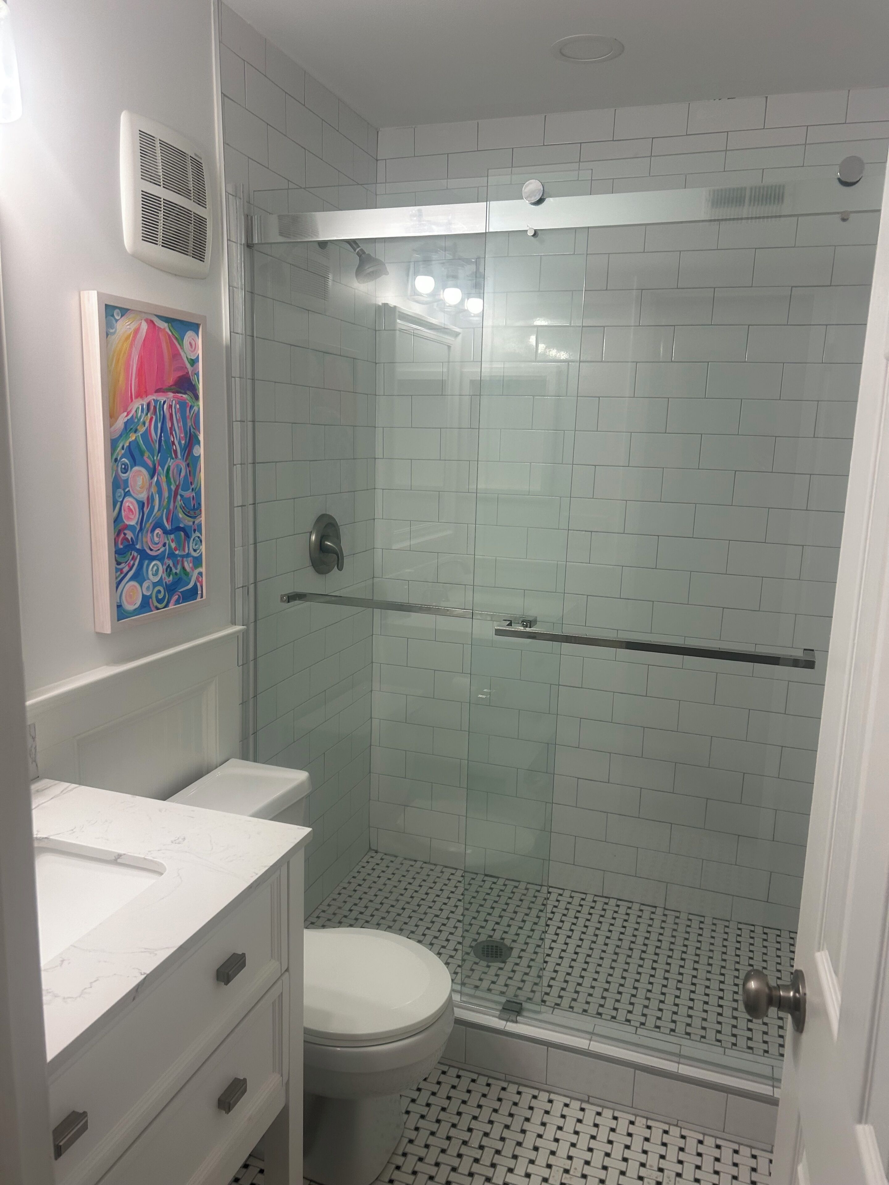 Een badkamer met douche, toilet en wastafel.