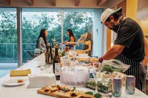 A dining area with a long table set for a meal, various food items, and bottles of beverages. - Thanksgiving in Austin | Chef’s Kitchen + Hot Tub (West Lake Hills)