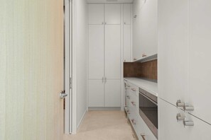 A narrow hallway with white cabinets, a wooden door, and a tiled floor. - Thanksgiving in Austin | Chef’s Kitchen + Hot Tub (West Lake Hills)