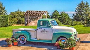 A vintage green and white truck parked in front of a wooden structure with 'O'HUT BAY' signage. - 2BR Oyhut Bay Condo | Fireplace | Private Deck (Ocean Shores)