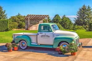 A vintage green and white truck parked in front of a wooden structure with 'O'HUT BAY' signage. - 2BR Oyhut Bay Condo | Fireplace | Private Deck (Ocean Shores)