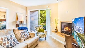 A living room with a sofa, armchair, fireplace, and a TV. - 2BR Oyhut Bay Condo | Fireplace | Private Deck (Ocean Shores)
