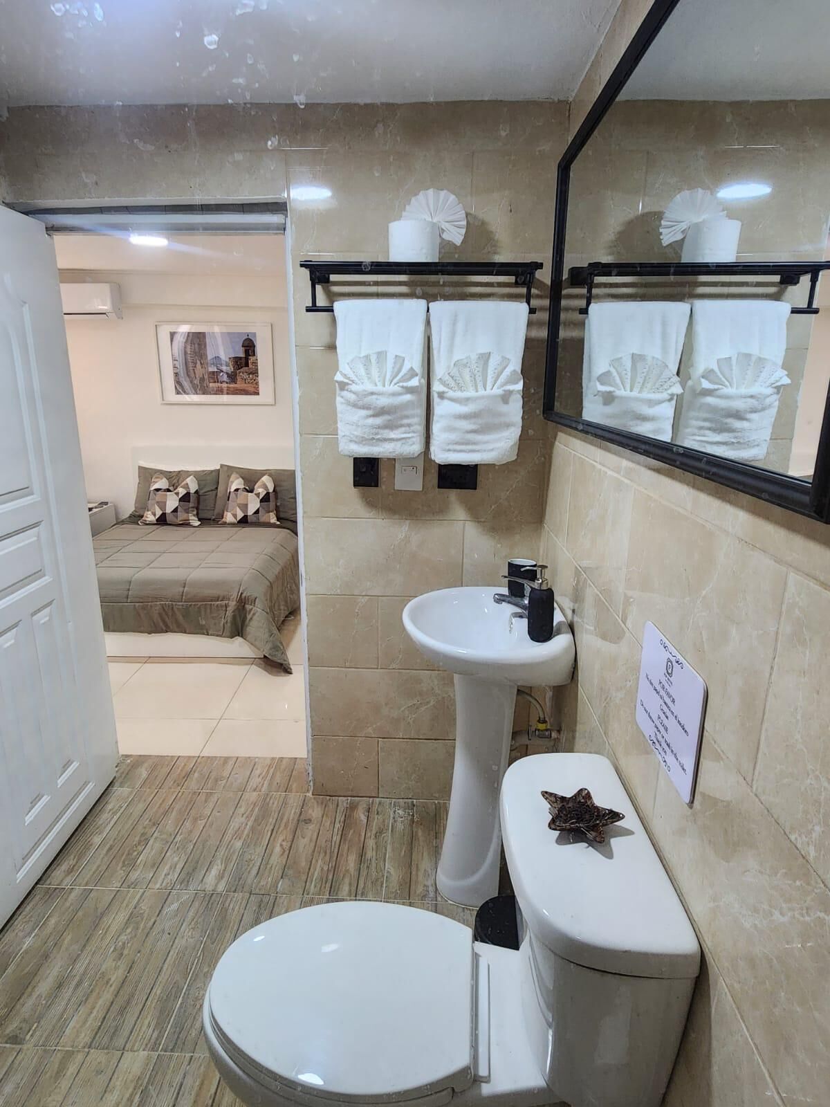Une salle de bain équipée de toilettes, d’un lavabo et d’un porte-serviettes.
