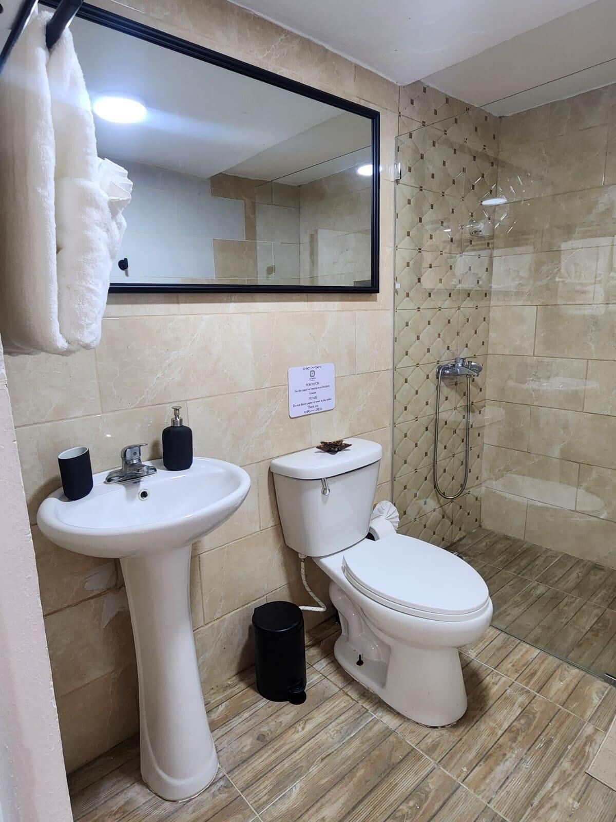 A bathroom with a pedestal sink, toilet, and a shower stall.