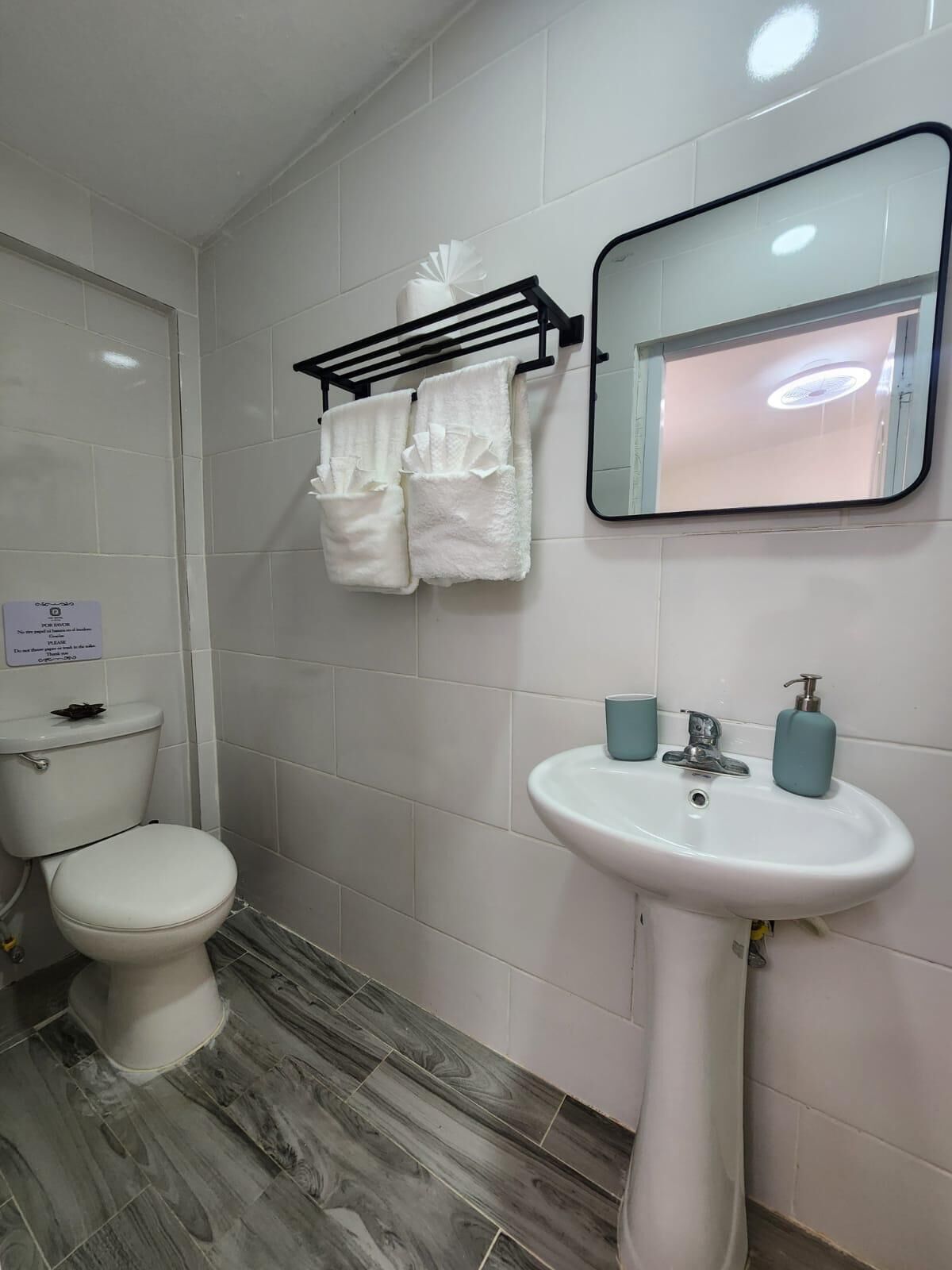 Une salle de bain comprenant des toilettes, un lavabo avec deux distributeurs de savon et un porte-serviettes avec deux serviettes.