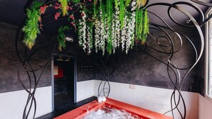 A spa room with a red hot tub, hanging greenery, and a modern interior design. - Boutique Hotel Liberata (L'Île-Rousse)