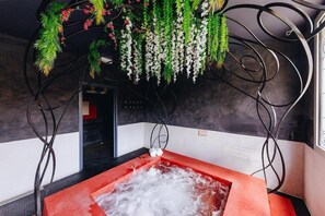 A spa room with a red hot tub, hanging greenery, and a modern interior design. - Boutique Hotel Liberata (L'Île-Rousse)