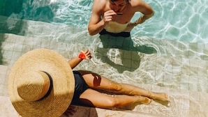 A person in a swimsuit and straw hat by a pool with clear water. - Boutique Hotel Liberata (L'Île-Rousse)